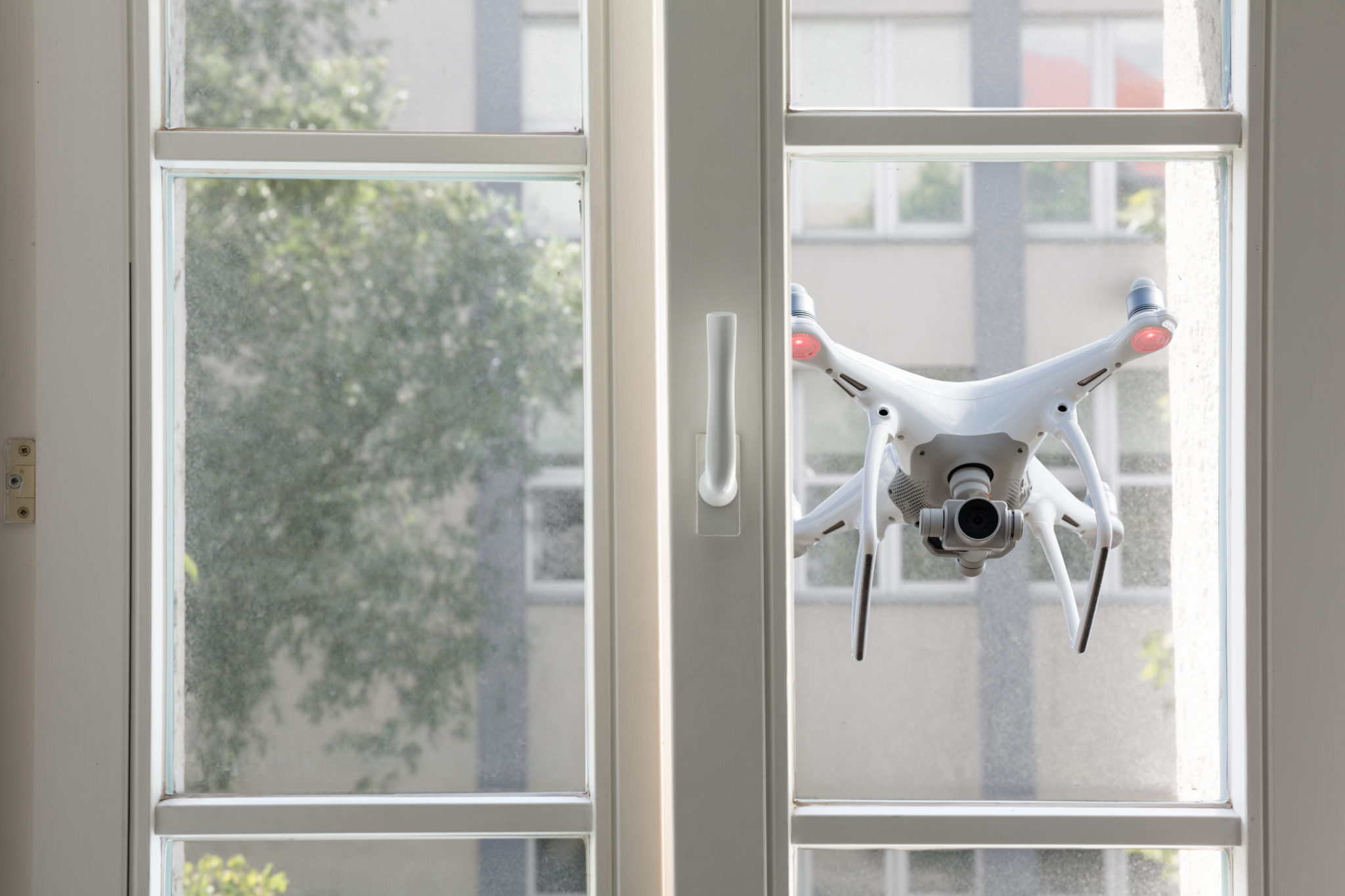 Eine fliegende Drohne spioniert durchs Fenster.