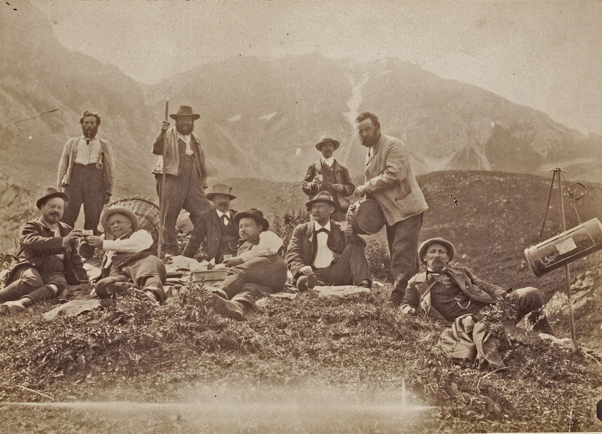 Auf dem Schwarz-weiss-Foto sieht man eine Gruppe Botaniker (alles Männer), die gerade auf einer Alpenwiese rasten.