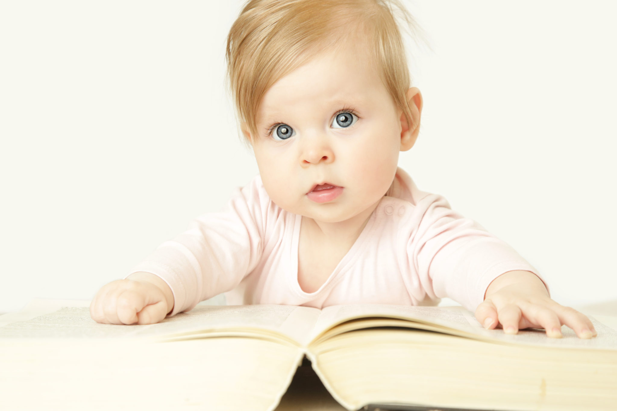 Adorable baby in front of big thick book, studio shot