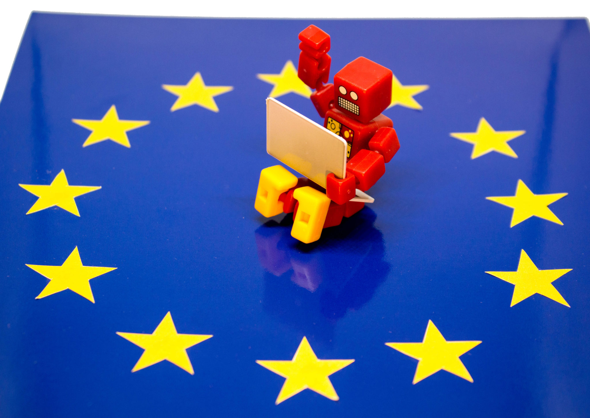 Lego-Roboter sitzt mit Laptop auf EU-Falgge.