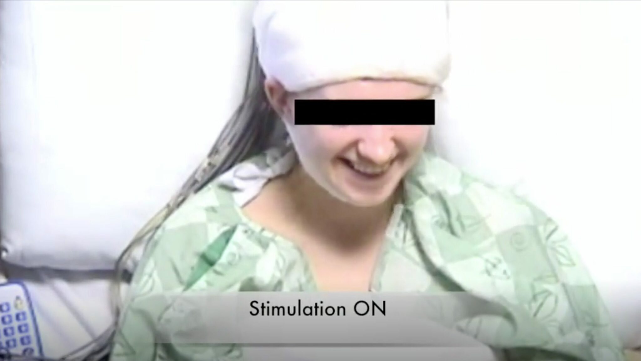 Eine Patientin sitzt im Bett und lächelt, kurz nachdem bei ihr eine Hirnregion stimuliert worden ist.