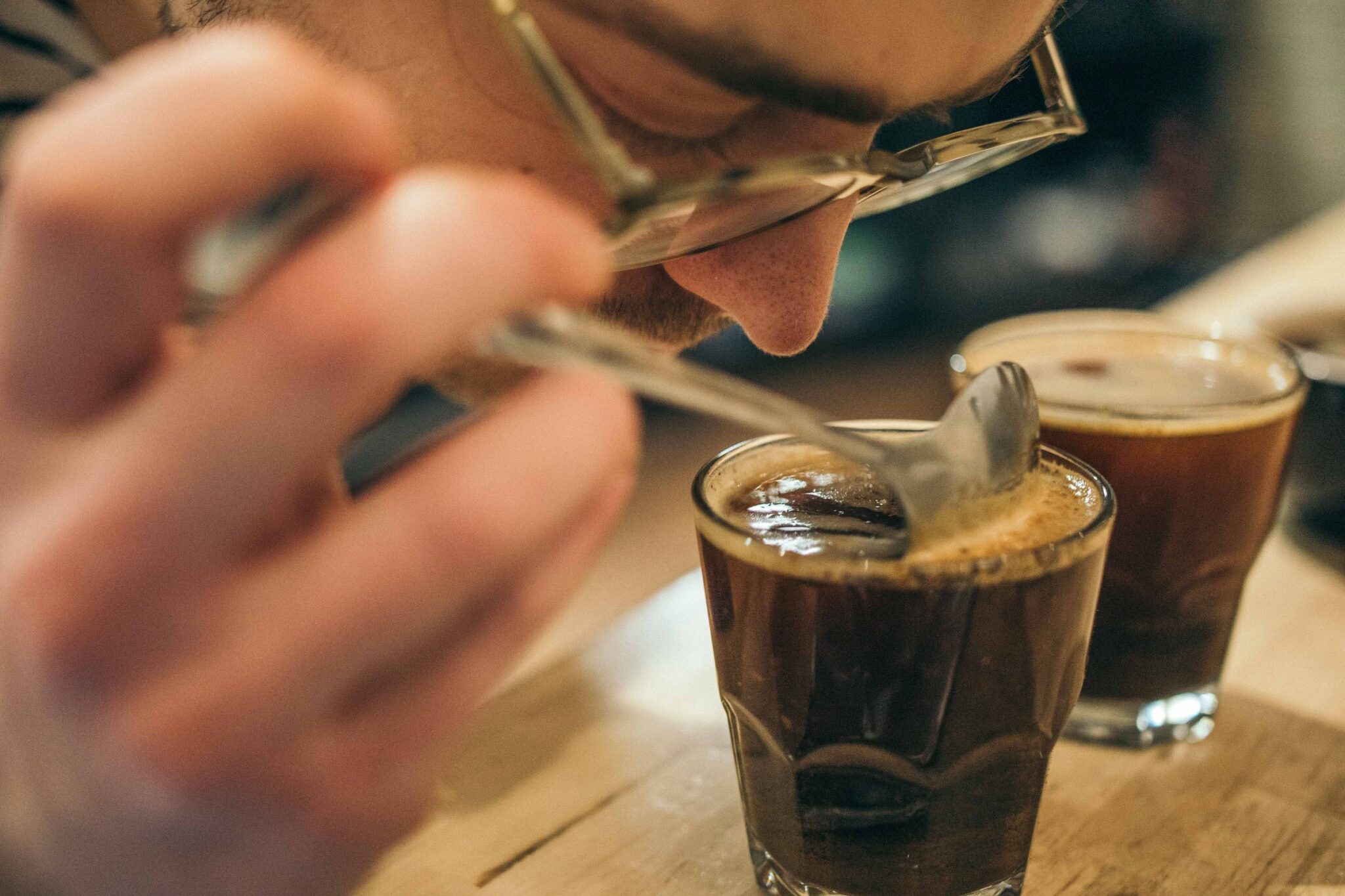 Ein Mann riecht an einem Glas mit Kaffee.