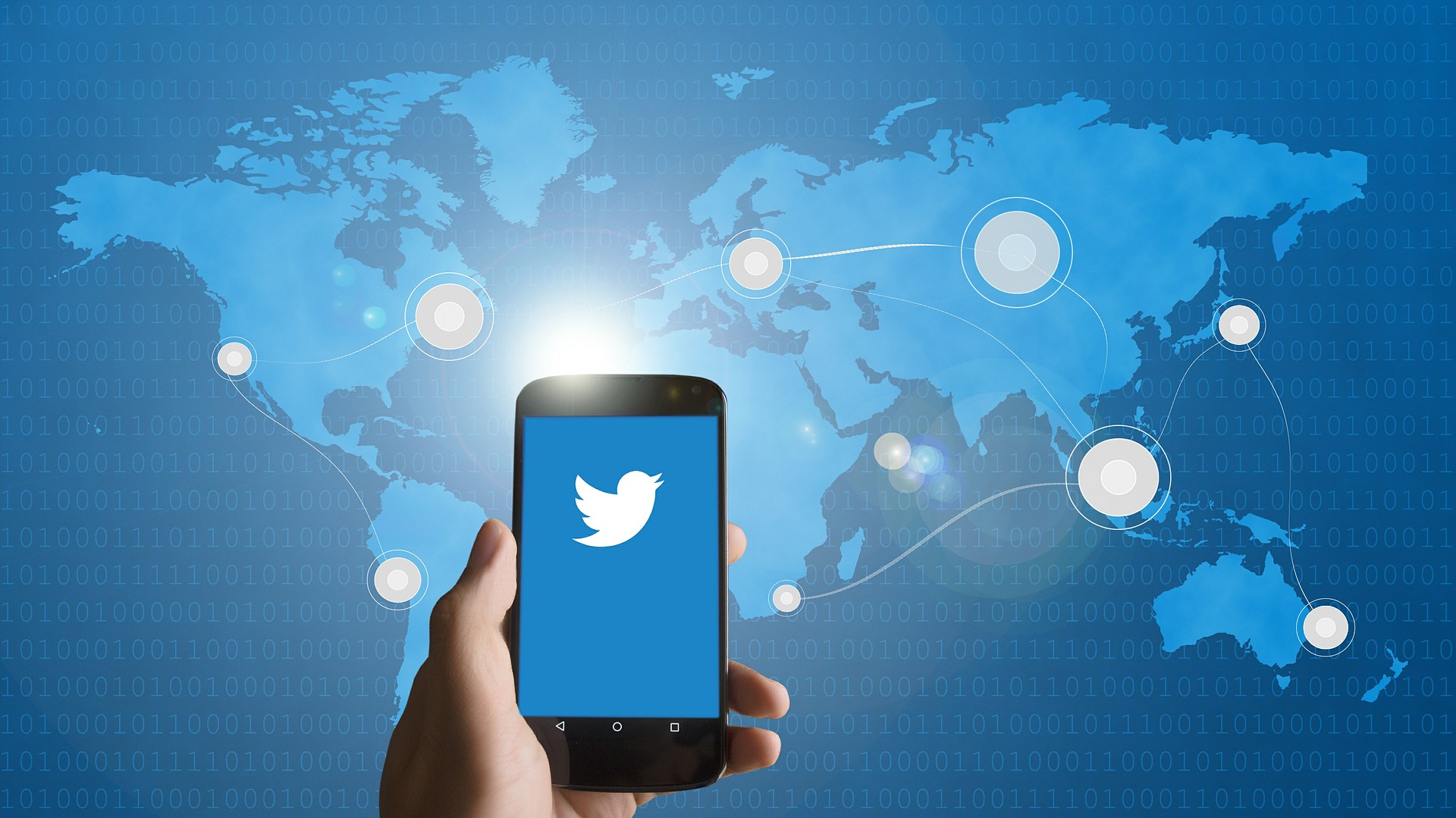 Handy mit Twitterlogo vor digitaler Weltkarte