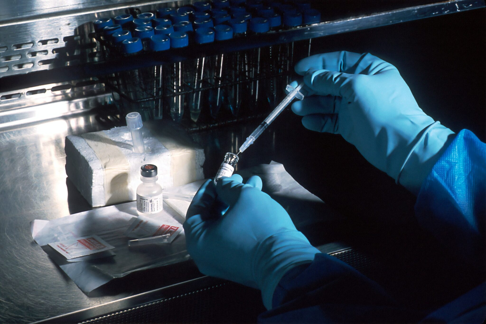 Blau behandschuhte Hände eines Forschers, der mit einem CEA-Antigen eine Spritze in steriler Umgebung aufzieht.