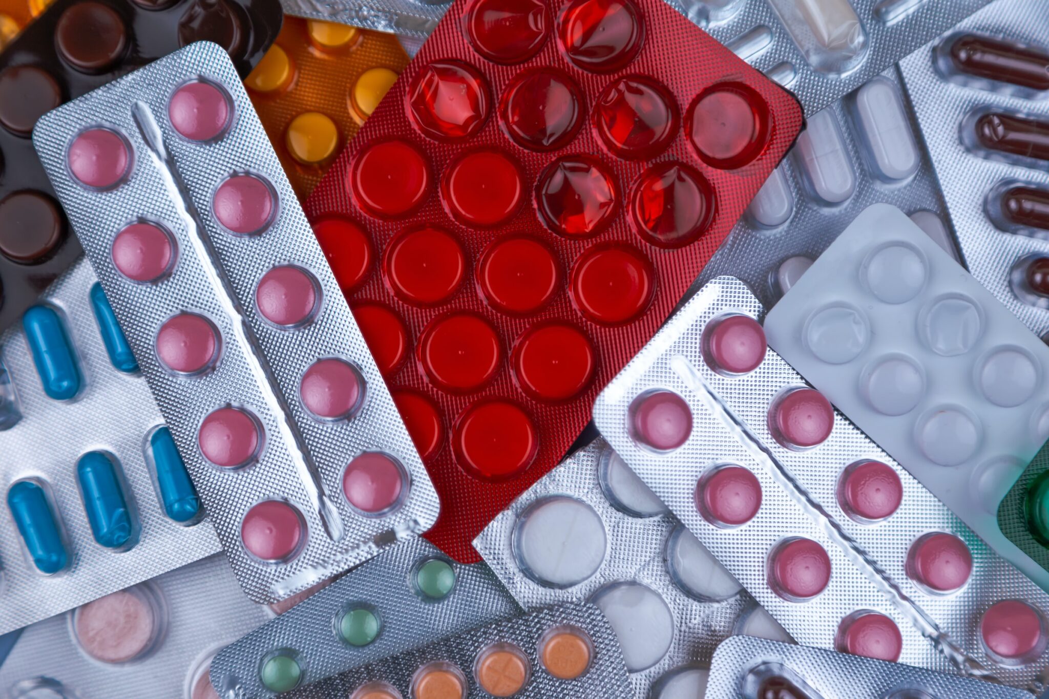 Ein Haufen medizinischer Pillen in weiss, blau und anderen Farben. Pillen in Plastikverpackung. Konzept der Gesundheitsfürsorge und Medizin.