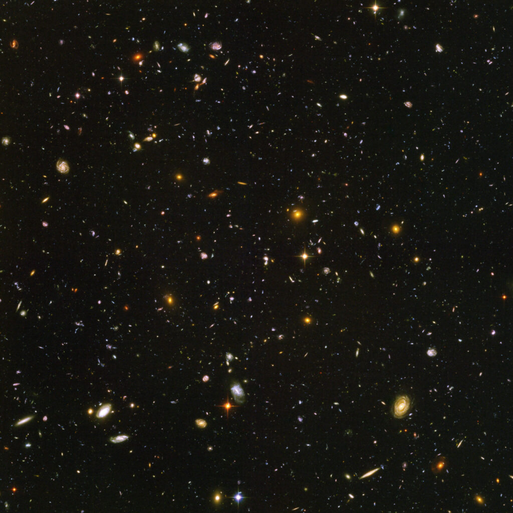Bild von weit entfernten Galaxien als bunte Punkte auf schwarzem Grund.