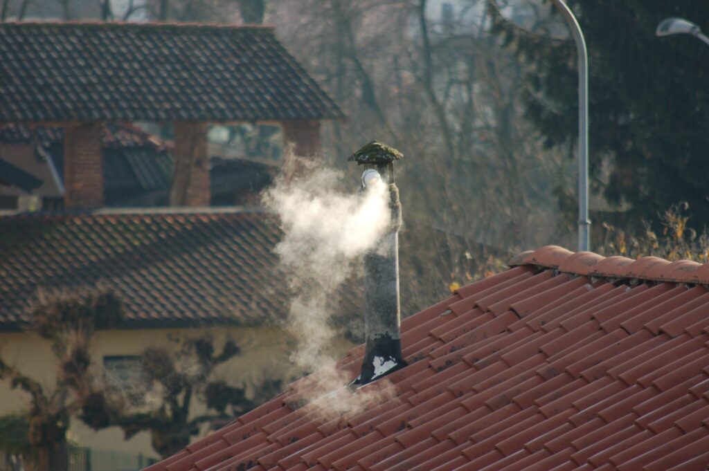 Rauchender Kamin auf einem Hausdach.