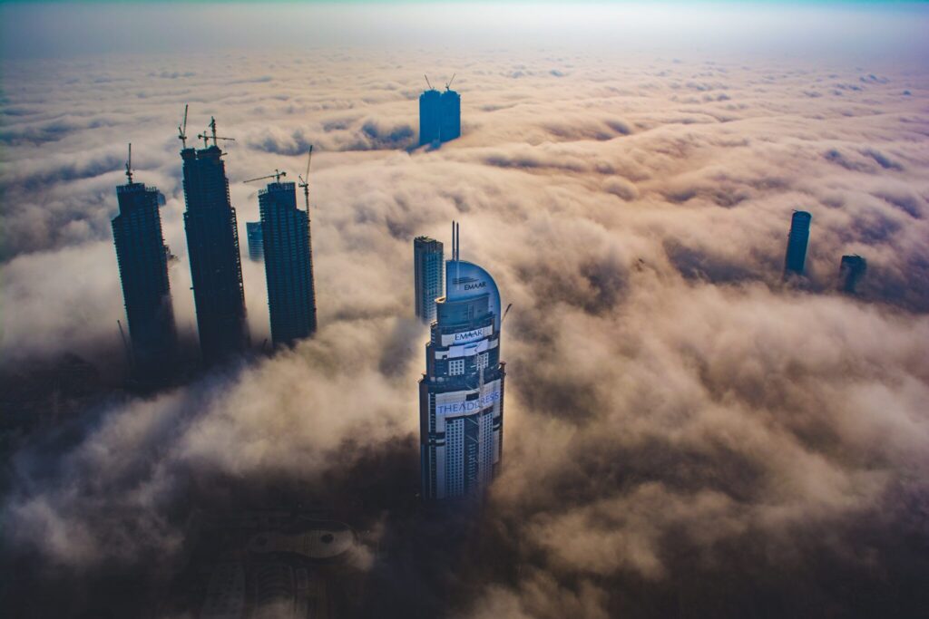 Blick aus dem Burj Khalifa, man sieht weit unten die Wolken von oben und auch andere Hochhäuser ragen über die Wolken hinaus.